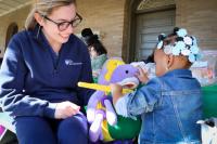 Penn Dental student Alexia Blackhurst shows an Early Head Start student how to properly brush teeth using a stuffed animal puppet.